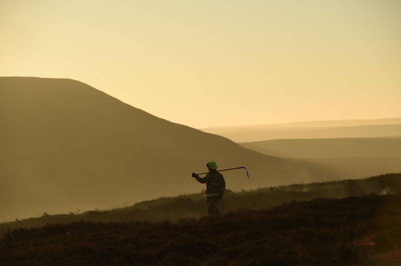 A firefighters walks across moorland as they tackle a blaze above Marsden. AFP