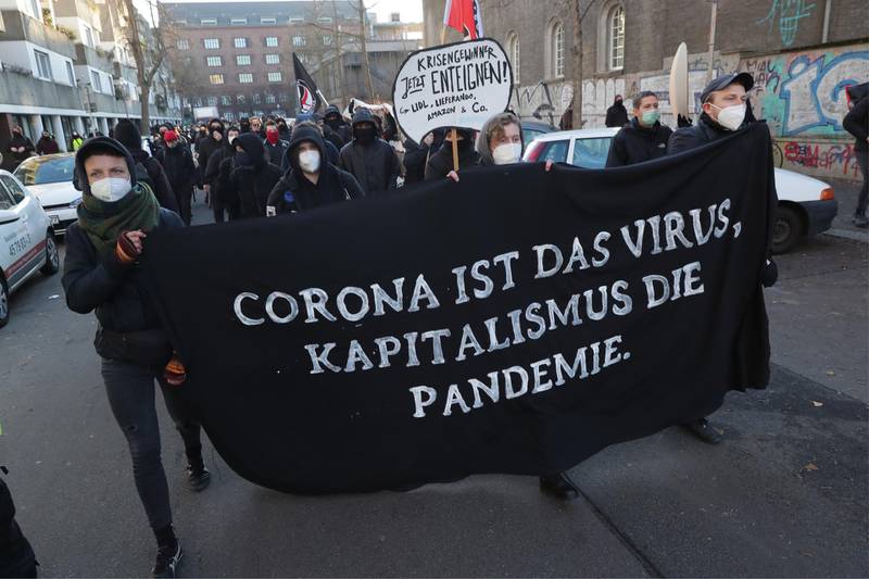 epa08911335 People participate in a demonstration 'FCK2020 - For a better tomorrow' in Berlin, Germany, 30 December 2020. Protesters are against coronavirus conspiracy ideologues and for dignified health, a fair education, labor rights and labor protection. The banner reads ‘Corona is the virus, capitalism is the pandemic’.  EPA/HAYOUNG JEON
