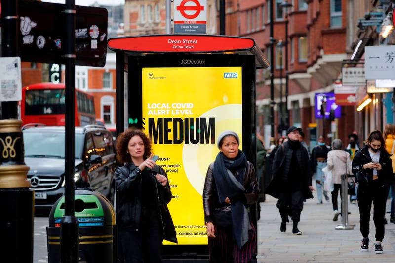 Pedestrians walk past a NHS sign displaying guidelines during the novel coronavirus COVID-19 pandemic, on a bus-stop shelter in the West End of London on October 14, 2020.  Prime Minister Boris Johnson on Wednesday said a new UK-wide lockdown would be a "disaster" but refused to rule it out as demands grew for a temporary shutdown to stop the spread of coronavirus.
 / AFP / Tolga AKMEN
