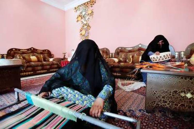 Hamda Al Mazrouei weaves a tablecloth while her mother Shamsa Al Mazrouei weaves a traditional basket in Madinat Zayed. Sarah Dea / The National