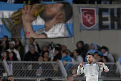 Lionel Messi on the pitch in front of a banner of him kissing the World Cup trophy at the Monumental stadium in Buenos Aires. AFP