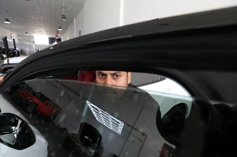 Mohammed Saidur fits window tints on a vehicle to reduce exposure to the sun. Chris Whiteoak / The National