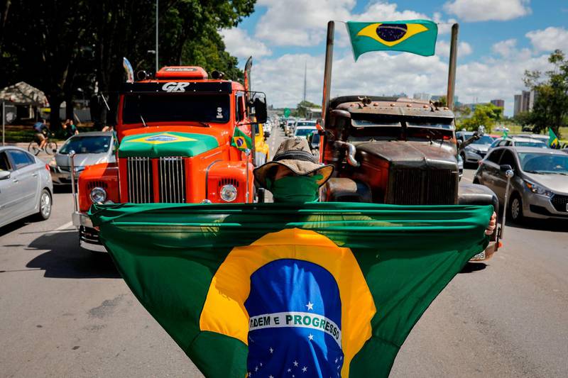 A supporter of anti-quarantine Brazilian President Jair Bolsonaro displays a Brazilian flag during a motorcade against the president of the Chamber of Deputies Rodrigo Maia and the quarantine and social distance measures imposed by governors and mayors to combat the novel coronavirus COVID-19 outbreak, in Brasilia. A total of 202,994 people have died worldwide since the epidemic surfaced in China in December, according to an AFP tally at 1100 GMT Sunday based on official sources.  AFP