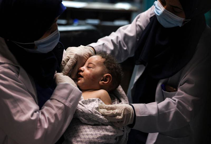 A nurse at Al Shifa Hospital holds a baby, who was pulled alive from under the rubble while seven other family members perished after an Israeli air strike struck Al Shati Refugee Camp in Gaza City. AFP