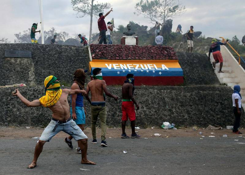Venezuelan demonstrators throw stones during clashes with authorities at the border between Brazil and Venezuela. AP Photo