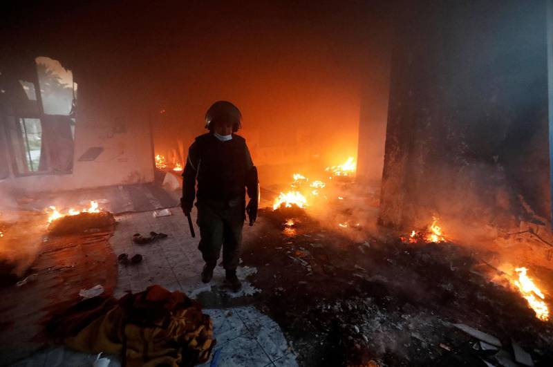A member of the security forces walks inside a burning building. Reuters