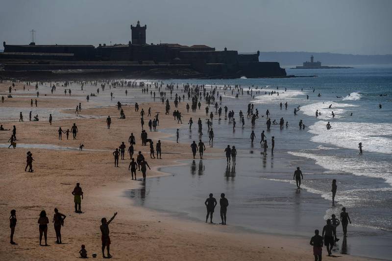 People enjoy the sun at Carcavelos beach in Cascais in the outskirts of Lisbon as temperatures rise and the Portuguese government loosens a lockdown put in place to slow the spread of the coronavirus.  AFP