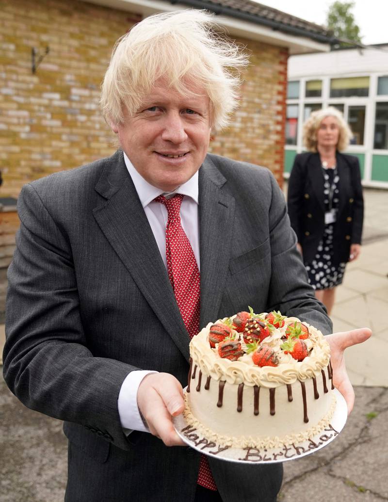 Boris Johnson holding a birthday cake presented to him by the staff during a socially distanced visit to Bovingdon Primary School in Hertfordshire on June 19, 2020. AFP