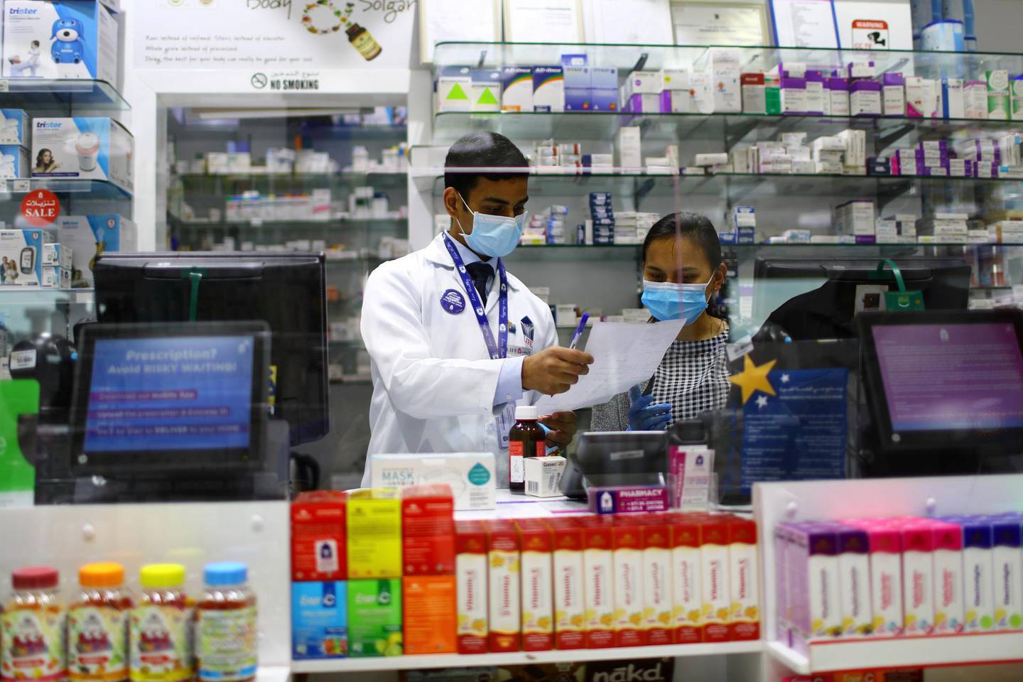 Pharmacists are seen behind a counter covered by glass, during the 24 hour lockdown to counter the coronavirus (Covid-19) outbreak in Dubai, United Arab Emirates April 6, 2020. REUTERS/Ahmed Jadallah