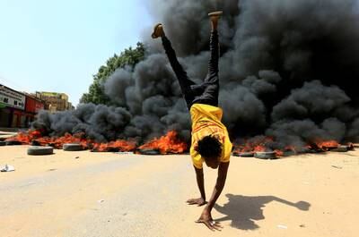 A person does a handstand in front of a burning pile of tyres during a pro-civilian rule protest against any military takeover in Khartoum on October 21. Reuters