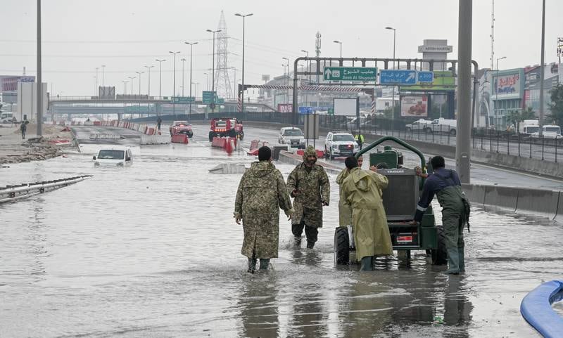 Kuwaiti military firemen wade through flood water. EPA