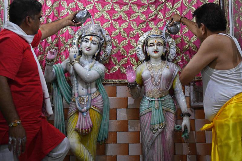 Priests pour milk and water on the idols of Hindu deities Krishna and Radha on the eve of Janmashtami in Amritsar. AFP