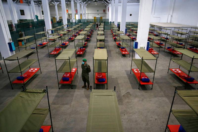 A Spanish soldier stands next to beds set up at a temporary hospital for vulnerable people at the Fira Barcelona Montjuic centre in Barcelon.  AFP