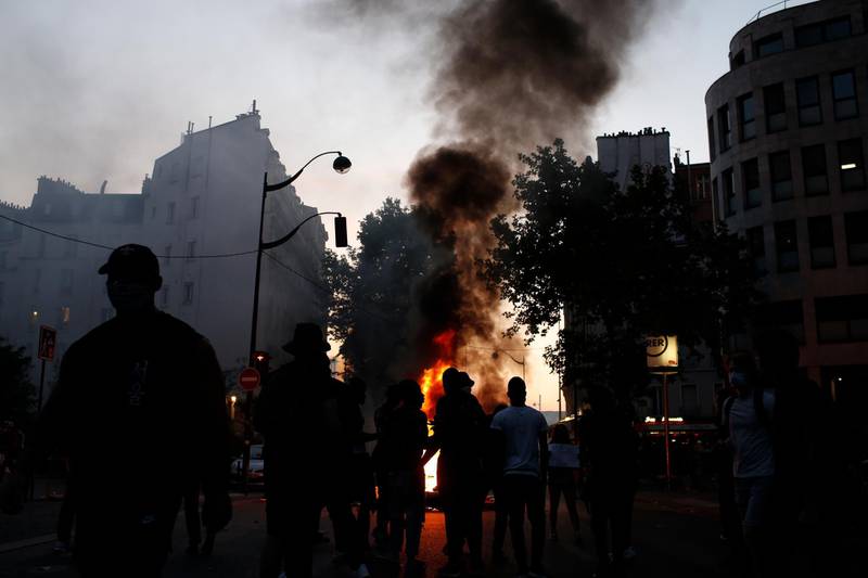 Protesters stand by a fire during a demonstration Tuesday, June 2, 2020. Paris riot officers fired tear gas as scattered protesters threw projectiles and set fires at an unauthorized demonstration against police violence and racial injustice. Several thousand people rallied peacefully for two hours around the main Paris courthouse in homage to George Floyd and to Adama Traore, a French black man who died in police custody. (AP Photo/Rafael Yaghobzadeh)