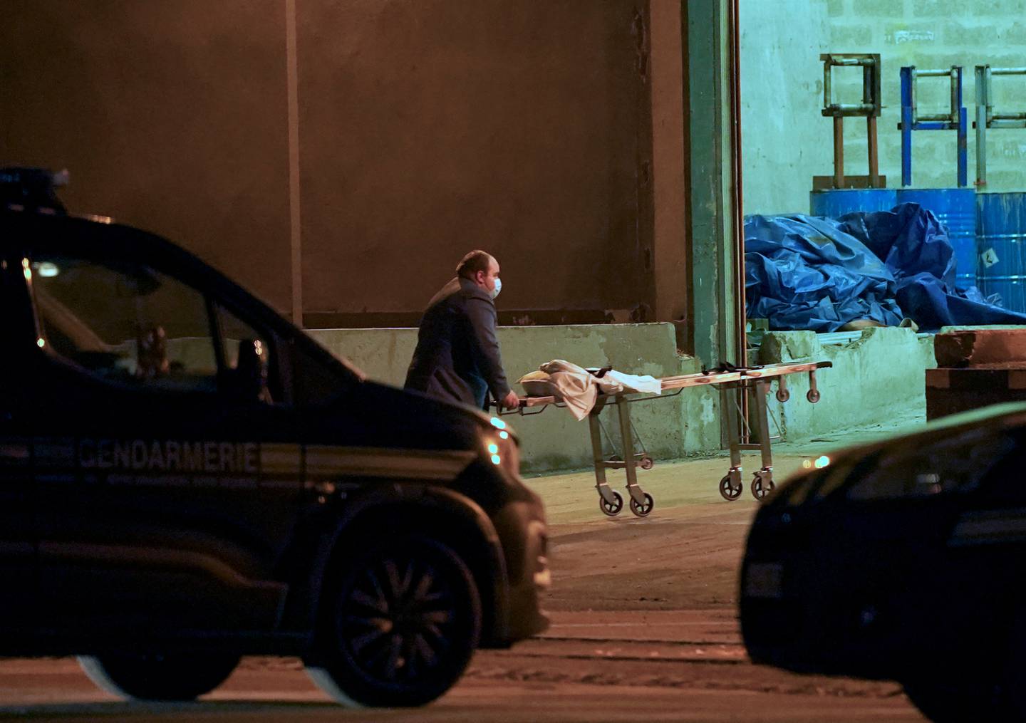 A man wheels a gurney into a warehouse in the Port of Calais, France, where it is believed the bodies of migrants are being transported. PA