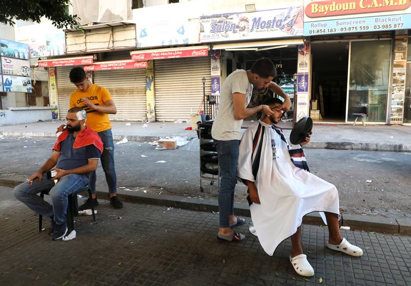 Barbers shave customers outside their shop after a power cut in Beirut. Reuters