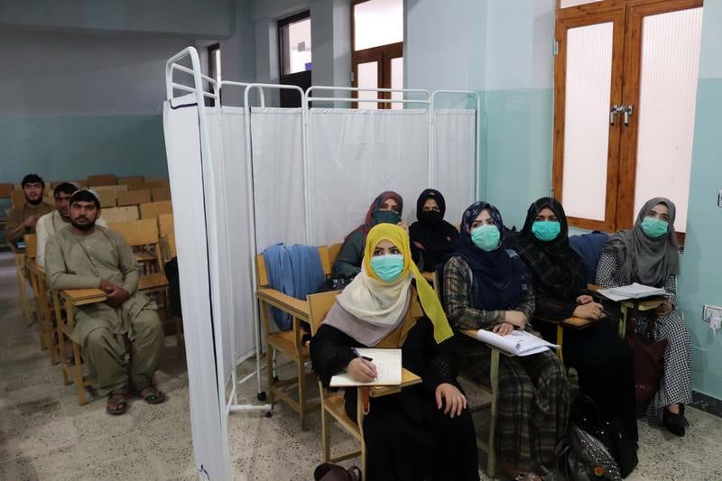 Afghan students separated by a partition attend a class at Mirwais Neeka University in Kandahar on September 20, 2021. The Taliban had officially announced the segregation of male and female students in all government and private universities. EPA