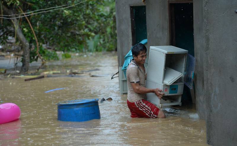A resident carries a plastic cabinet inside their flooded house after a heavy downpour due to exiting Tropical storm Yagi, submerged homes in Marikina City, suburban Manila on August 12, 2018. AFP