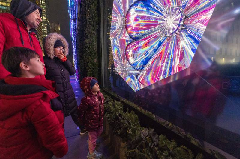 A family takes in the holiday window display at Saks Fifth Avenue in New York. AP