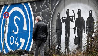 A man passes graffiti on wall with the logo of Schalke.. The traditional club, founded by miners in 1904, faces one of its biggest crises, as the club will most likely have to relegate to the second division. AP
