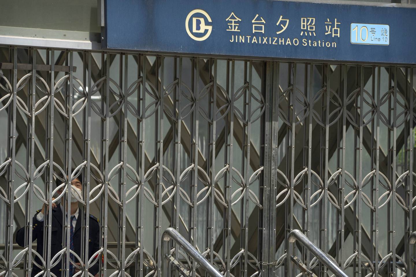 A masked member of staff at the gates of the closed subway station in Beijing on Wednesday. AP