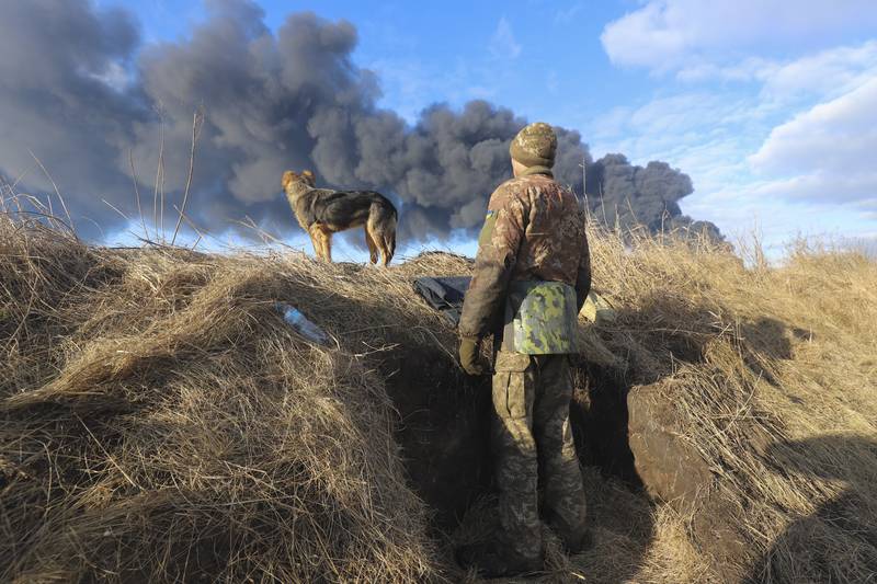 A Ukrainian serviceman and his dog look at smoke from a burning fuel depot after a Russian missile strike near Kiev, Ukraine. EPA