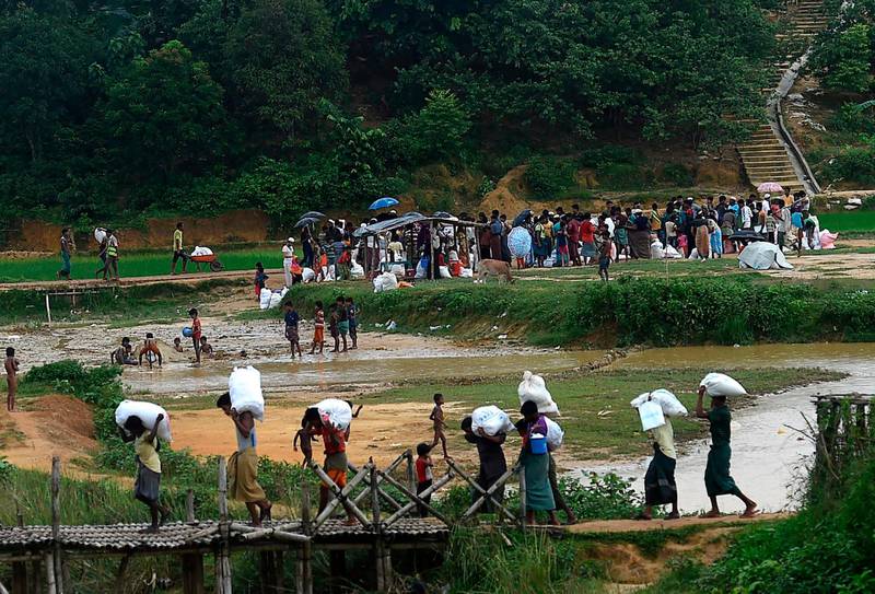 Rohingya people walk back to their house after collecting relief material in Kutupalong refugee camp, in Ukhia on August 24, 2020. / AFP / Munir Uz zaman

