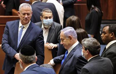 Mr Gantz, left, and Mr Netanyahu chat with Members of Parliament. AFP