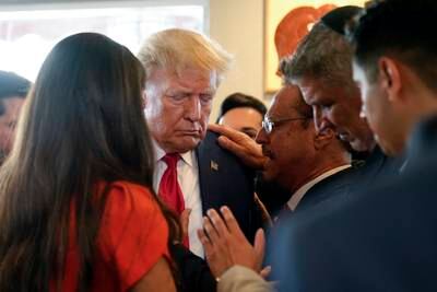 Mr Trump prays with a pastor and others at Versailles restaurant in Miami after his arraignment on felony charges. AP