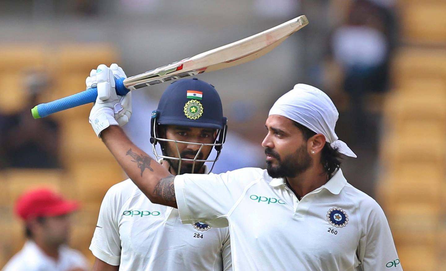 India's Lokesh Rahul, left, watches teammate Murali Vijay raise his bat to celebrate scoring a century during the one-off cricket test match against Afghanistan in Bangalore, India, Thursday, June 14, 2018. (AP Photo/Aijaz Rahi)