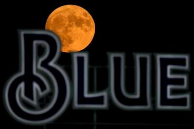 The blue supermoon rises beyond a sign during a baseball game in Kansas City. AP