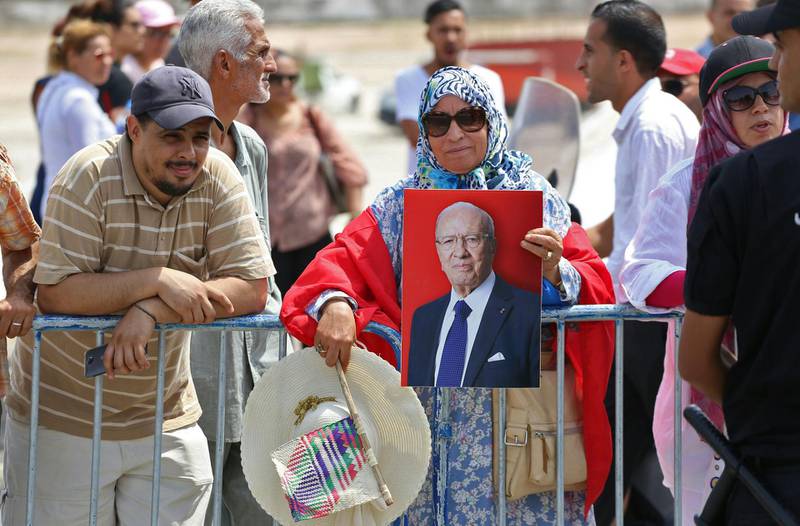 A Tunisian woman carries a portrait of the late president as people gather for the state funeral of late president Essebsi at the El-Jellaz cemetery in Tunis. AFP