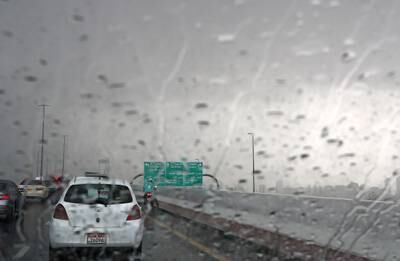 Traffic under grey skies and rain on Hessa Street in Dubai.
