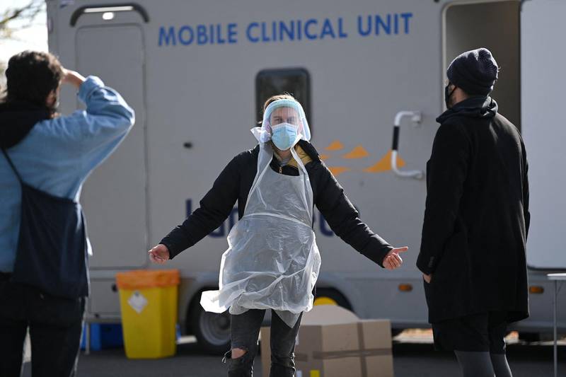 A worker dressed in PPE talks with members of the public arriving to take Covid-19 tests at a surge testing centre in Brockwell Park in south London. AFP