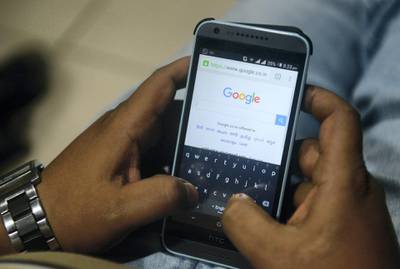 An Indian man surfs on his mobile phone using the Google search engine with its new logo, in Siliguri on September 2,2015.  Google refreshed its logo to better suit mobile devices that are supplanting desktop computers when it comes to modern Internet lifestyles.  The 17-year-old Internet company is keen to follow users of its online products onto new generations of Internet-linked devices such as smartphones, tablets and watches.  AFP PHOTO / Diptendu DUTTA / AFP PHOTO / DIPTENDU DUTTA