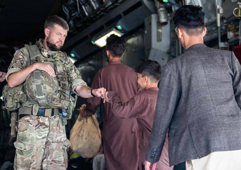A member of the UK Armed Forces fist-bumping an evacuee during their deployment to support the evacuation of British nationals and entitled personnel at Kabul airport. AFP