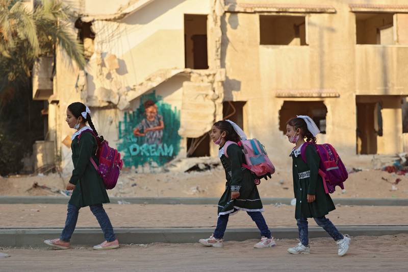 Children walk to school past buildings destroyed by war. AFP