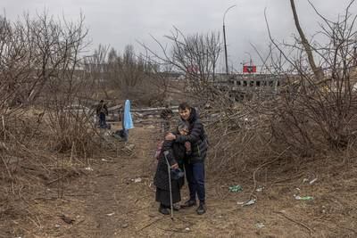A man hugs an elderly woman after crossing a damaged bridge as they flee from the frontline town of Irpin, near the Ukrainian capital of Kyiv. EPA