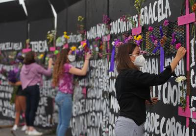 Women place flowers and posters adorned with the names of victims of femicide on metal fences during a protest against sex-based hate crimes in Mexico City, Mexico. EPA