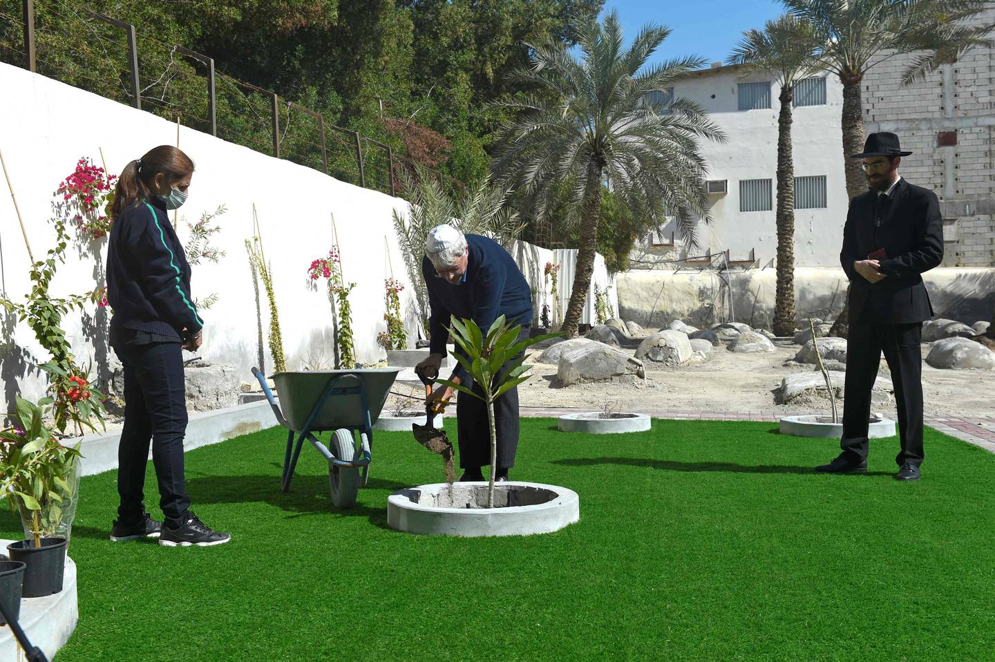 Ebrahim Nonoo, centre, head of the Jewish community in Bahrain, plants a tree as Rabbi Yaacov Phia, right, looks on at the Jewish cemetery in Bahrain's capital Manama, on January 23, 2022.  AFP