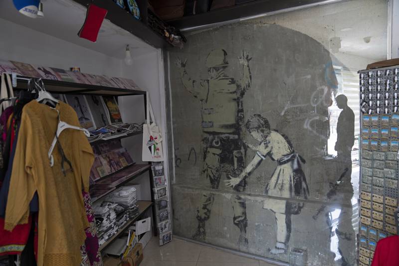 A different Banksy mural is covered with protective glass inside a gift shop in Bethlehem.