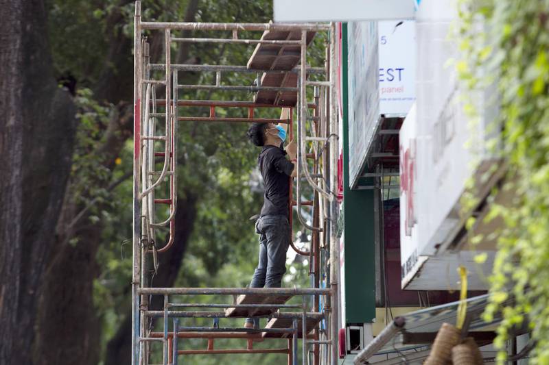 A worker wearing a protective mask stands on scaffolding in Ho Chi Minh City, Vietnam. Bloomberg