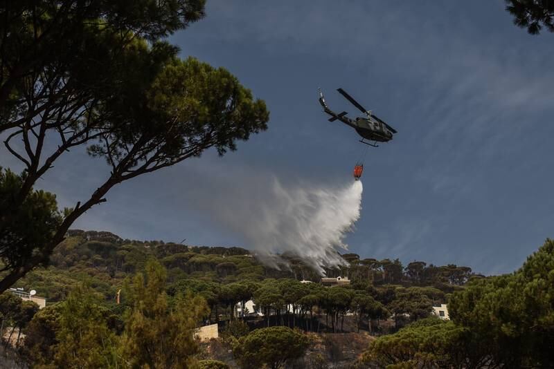 A helicopter dumps water on fires described by civil defence workers as '90% under control' following a round-the-clock battle to extinguish it before it could reach houses. All photos: Elizabeth Fitt