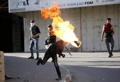 A Palestinian protester hurls a Molotov cocktail at Israeli troops, during clashes in the West Bank city of Hebron.  EPA