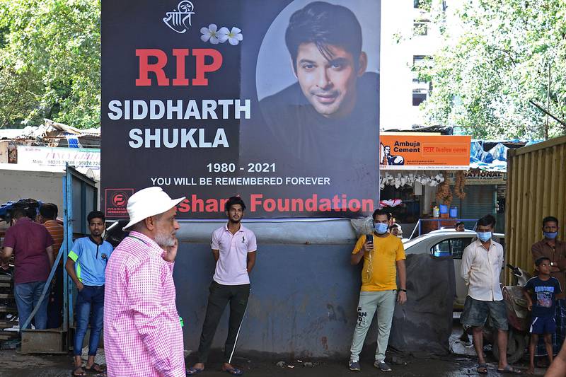 People stand in front of a poster of Indian actor Sidharth Shukla, a day after his demise in Mumbai on September 3, 2021. AFP