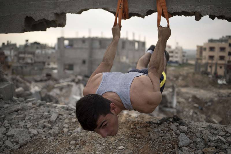 Palestinian Mahmoud Nasman, of team Bar Palestine, suspends during street exercises amid the destruction in Gaza City on August 3.
