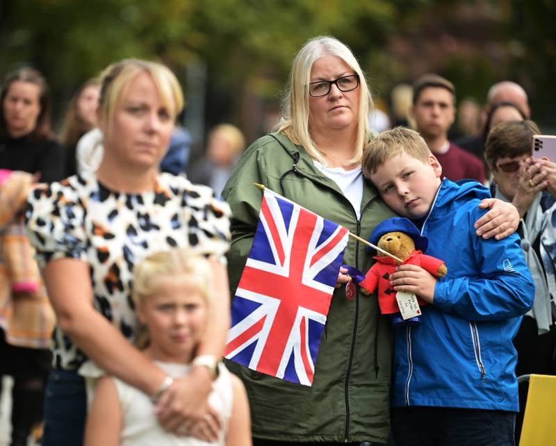 A young boy is comforted by his mother as crowds of people gather to watch the funeral on a screen near Belfast city hall. Getty Images