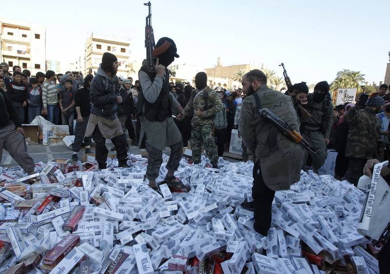 British teacher has been banned after funding ISIS fighters. Image shows ISIS fighters standing on confiscated cigarettes before setting them on fire in the city of Raqqa.  Reuters