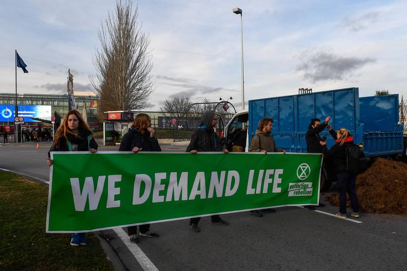 Activists from international climate action group Extinction Rebellion hold a banner reading "we demand life" after dumping manure outside the UN Climate Change Conference COP25. AFP