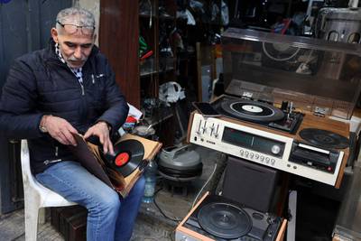 Palestinian Jamal Hemmou checks a collection of vinyl records in front of his shop in the occupied-West Bank city of Nablus, on January 17, 2023.  - Hemou, 58, is the last of his kind in Nablus in the West Bank city: He runs the only store in Nablus repairing and selling vinyl records and their players.  Like much of the world, Nablus is attuned to digital music, but Hemmou told AFP working with vinyl was about preserving Palestinian "heritage. " (Photo by JAAFAR ASHTIYEH  /  AFP)